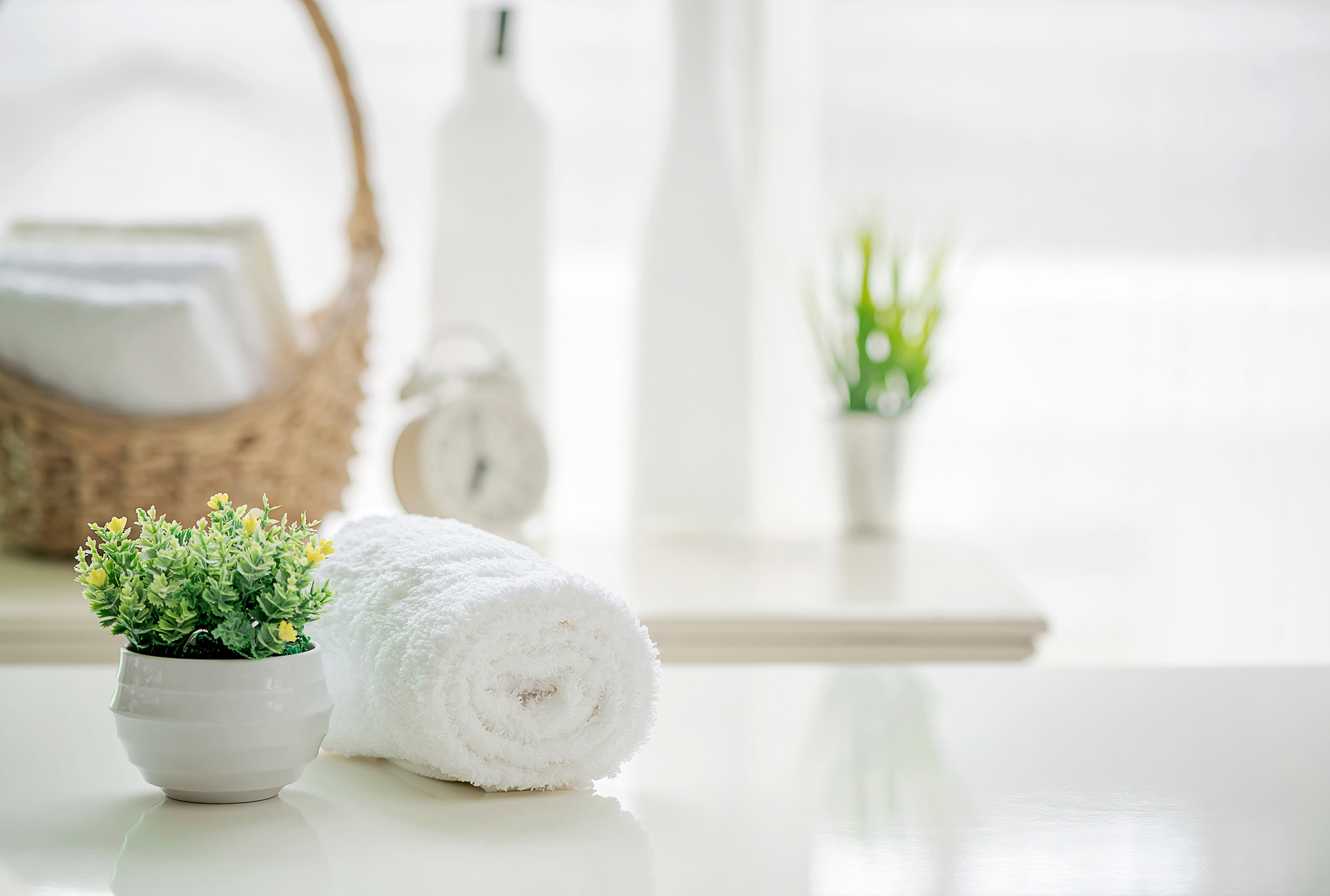 Roll up of white towels on white table with copy space on blurred living room background